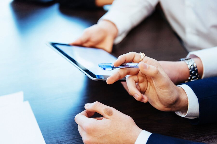 Administración y recuperación de la cartera de créditos analisis - Colaboración empresarial revisando información en una tablet.